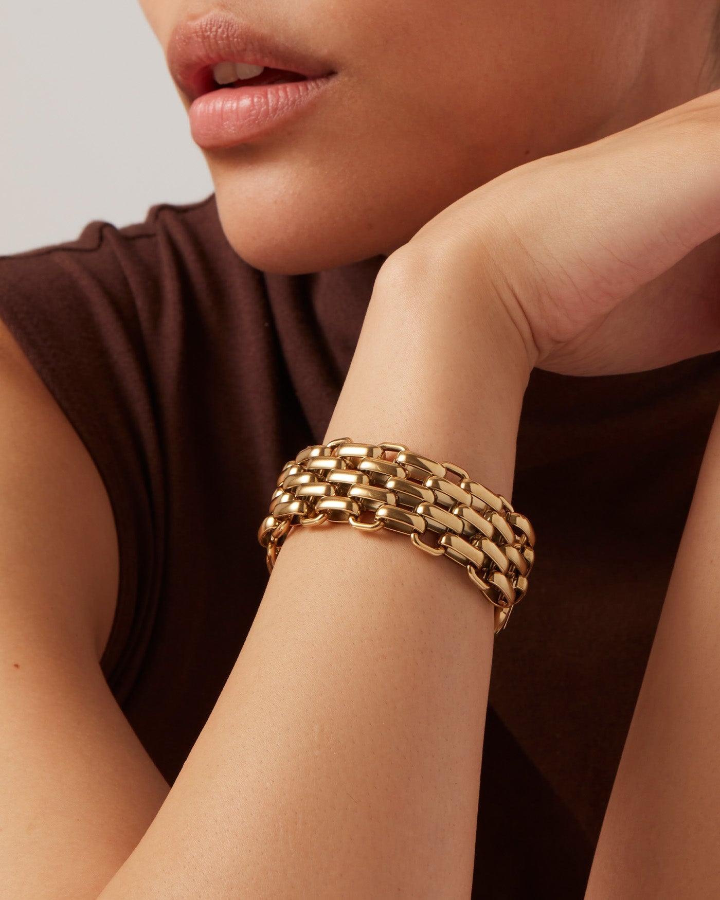 Portrait of a woman with braided hair, silver earrings, and a beige top.