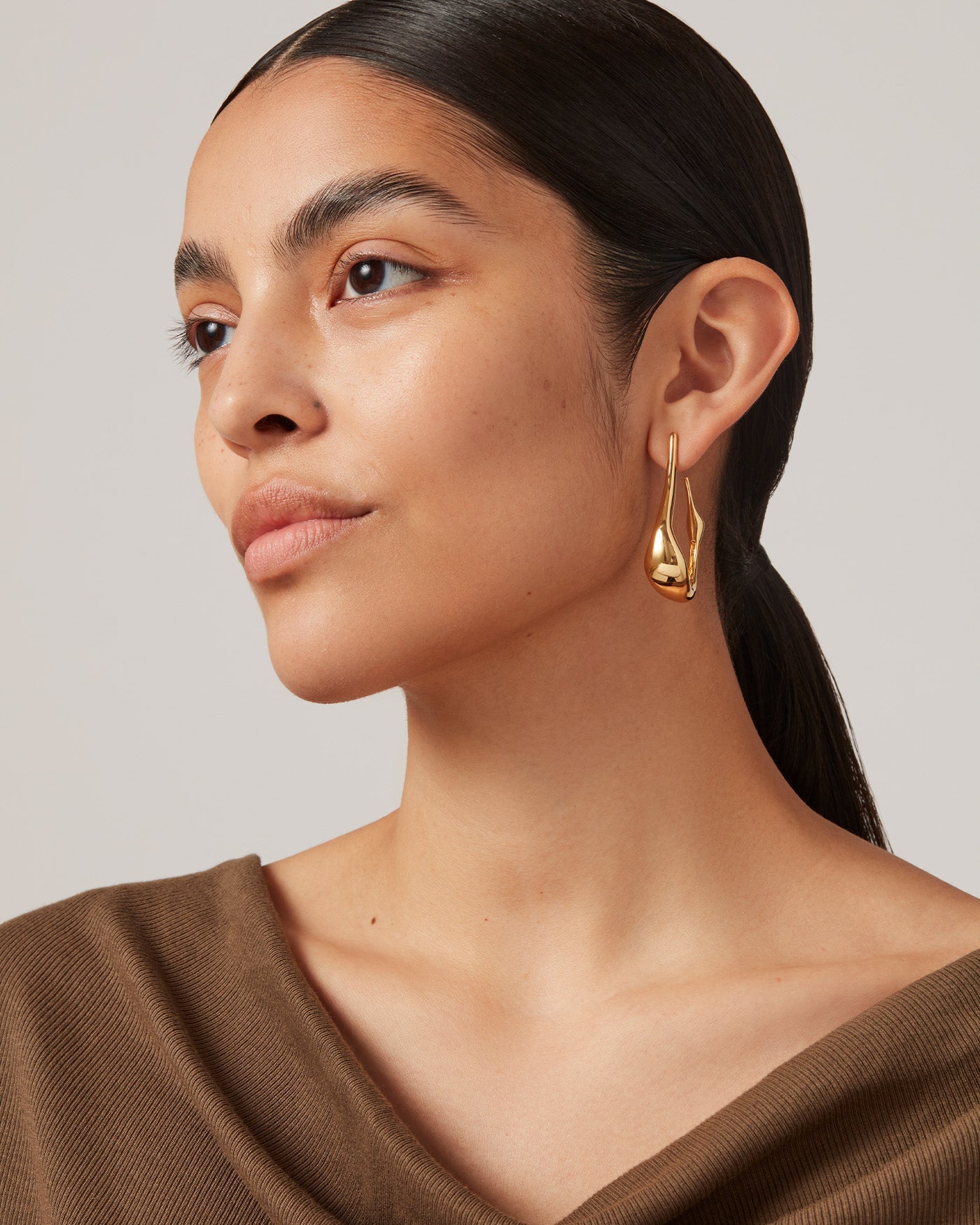 Woman wearing a large silver hoop earring with a close-up profile view.