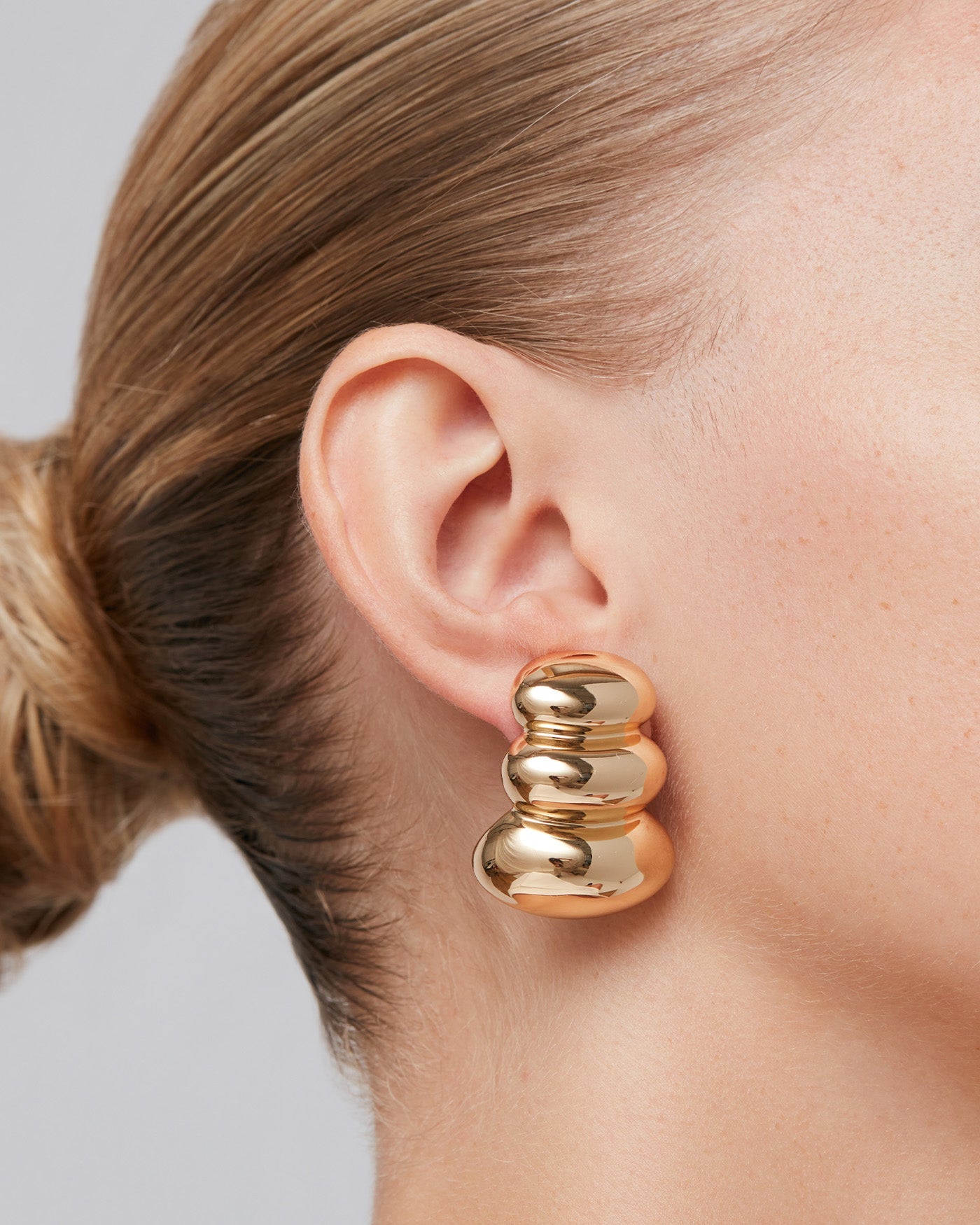 Woman wearing a large silver hoop earring with a close-up profile view.